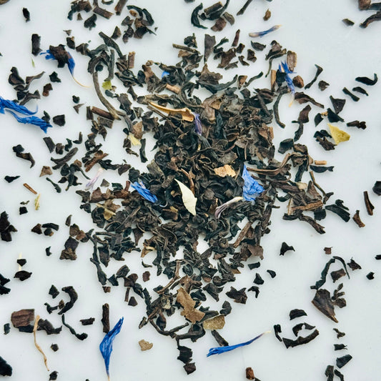 Loose leaf black tea leaves with cornflower blue flowers on a white background